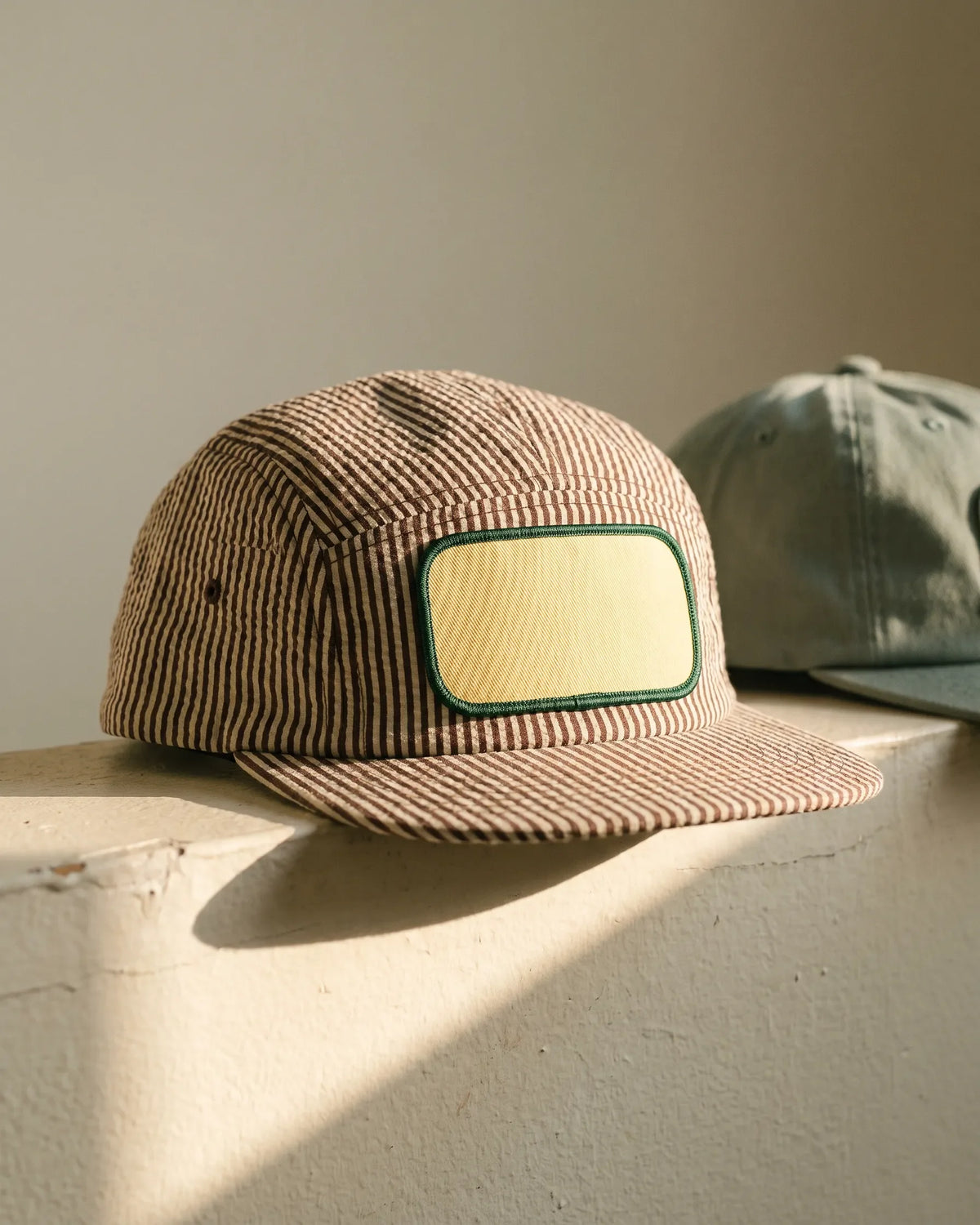 Chipper headwear tile - hickory stripe seersucker patch cap on a plaster ledge